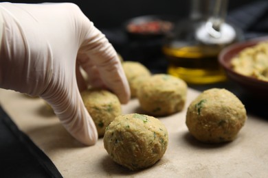 Photo of Cook making falafel balls at black table, closeup