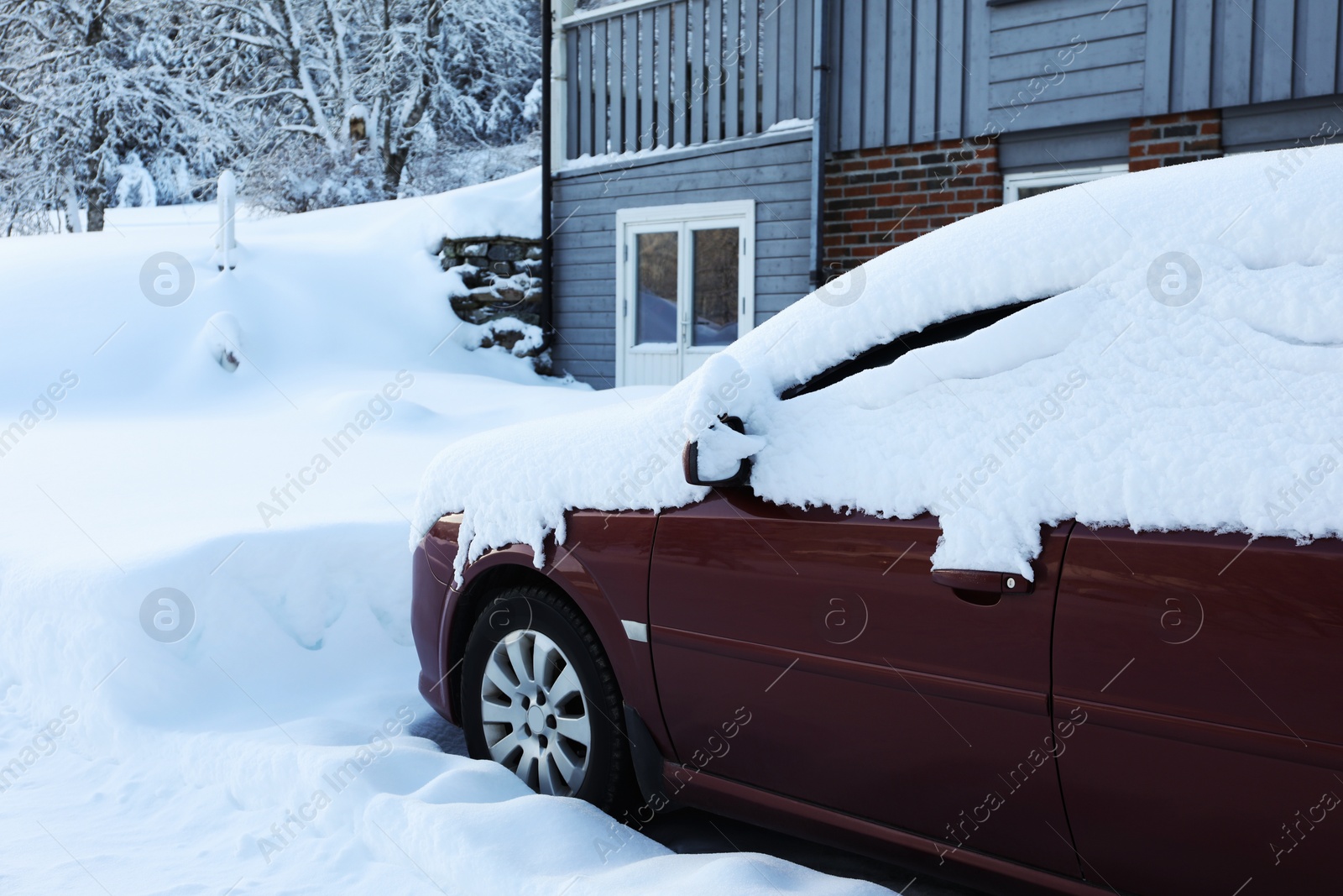 Photo of Modern car covered with snow near building on winter day