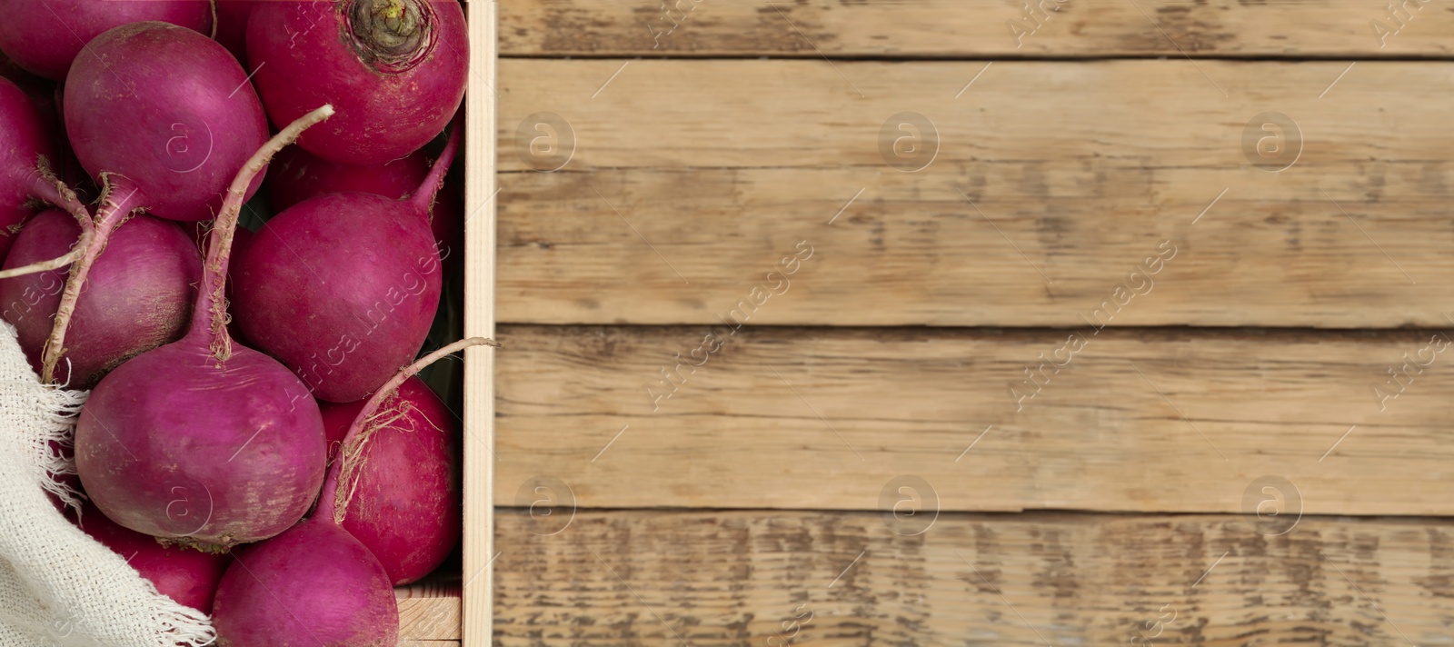 Image of Crate with red turnips on wooden table, top view. Space for text