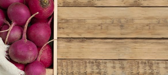 Image of Crate with red turnips on wooden table, top view. Space for text