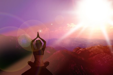 Woman meditating in mountains at sunset, back view