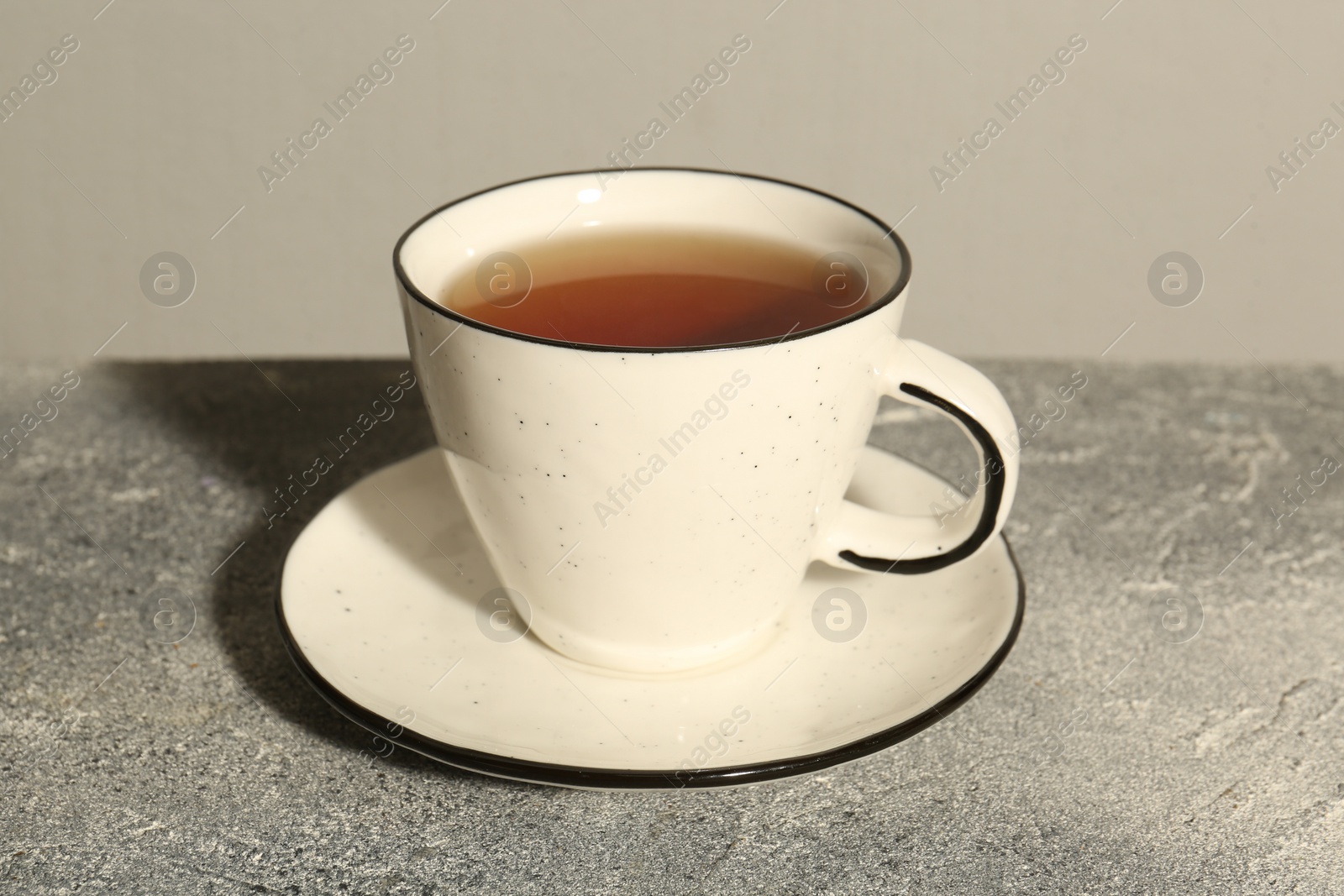 Photo of Aromatic tea in cup on grey table