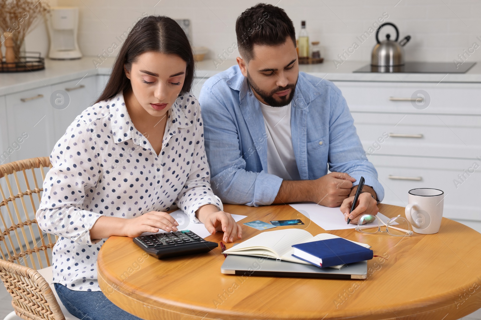 Photo of Young couple discussing family budget in kitchen