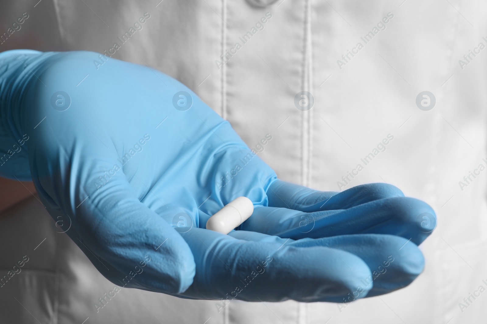 Photo of Doctor in medical glove holding pill, closeup view