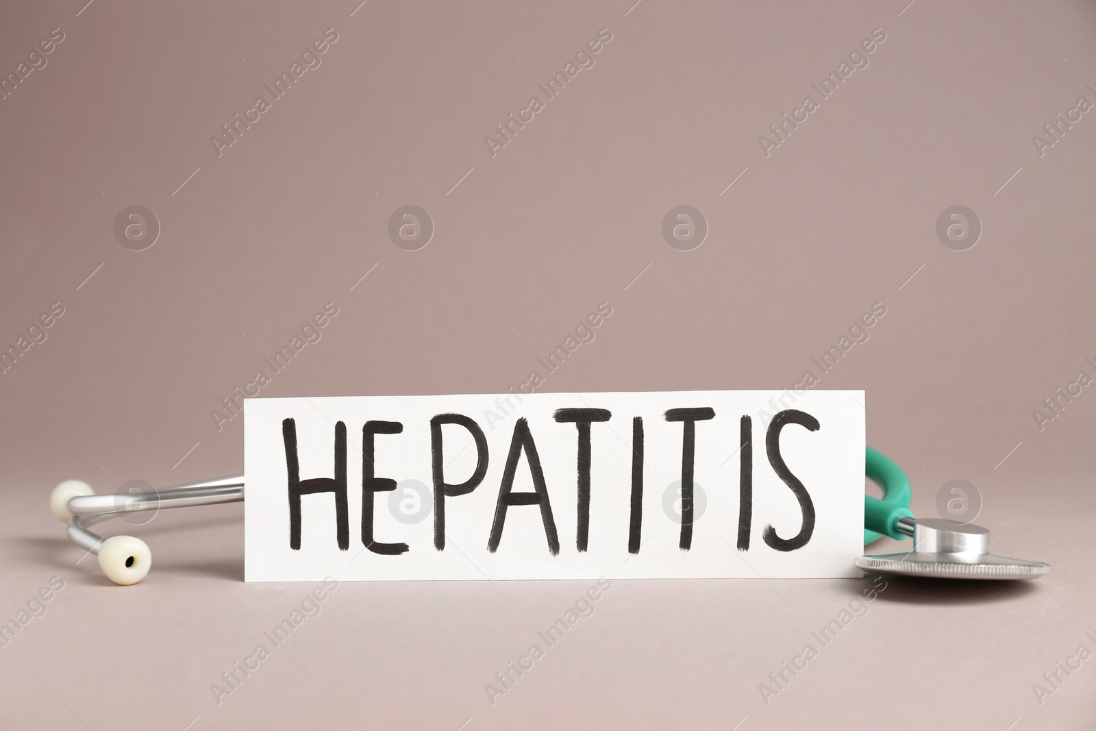 Photo of Word Hepatitis and stethoscope on beige background