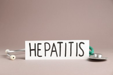 Photo of Word Hepatitis and stethoscope on beige background