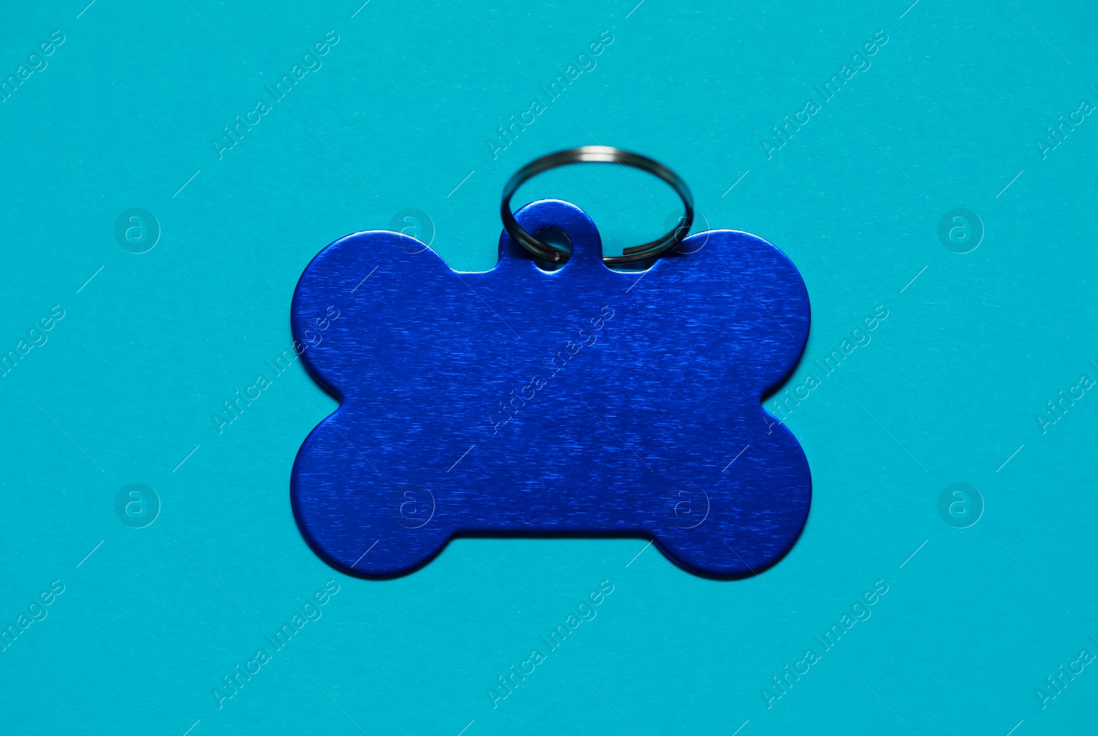 Photo of Pet tag in shape of bone with ring on light blue background, top view