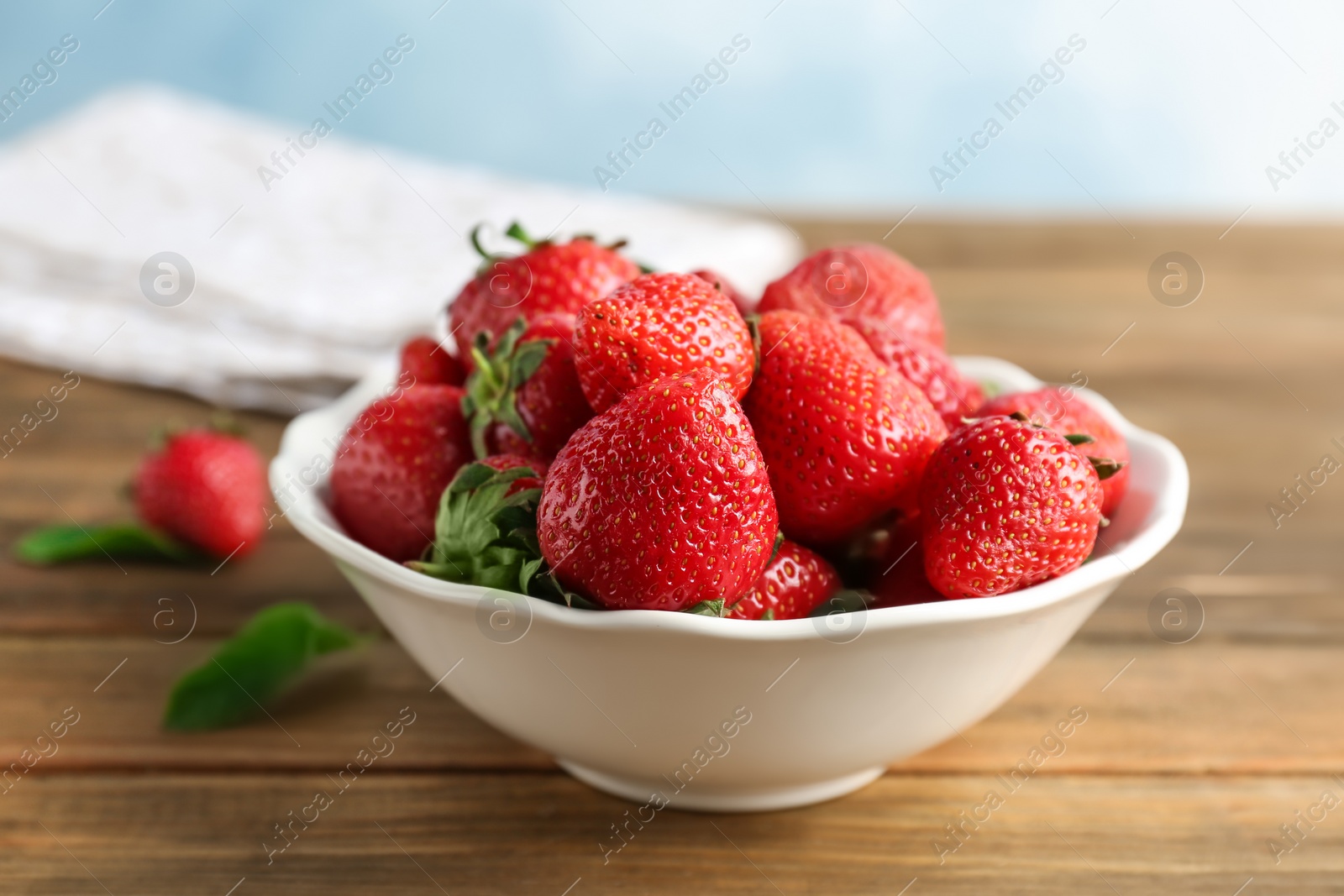 Photo of Bowl with ripe red strawberries on wooden table