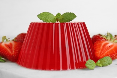 Stone board with fruit jelly, strawberries and mint on light background