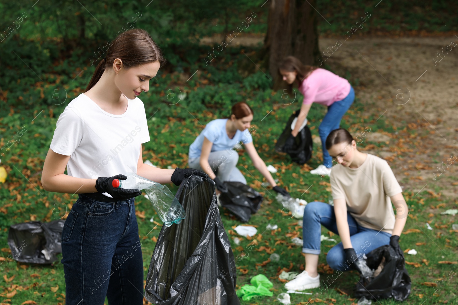 Photo of Group of people with plastic bags collecting garbage in park