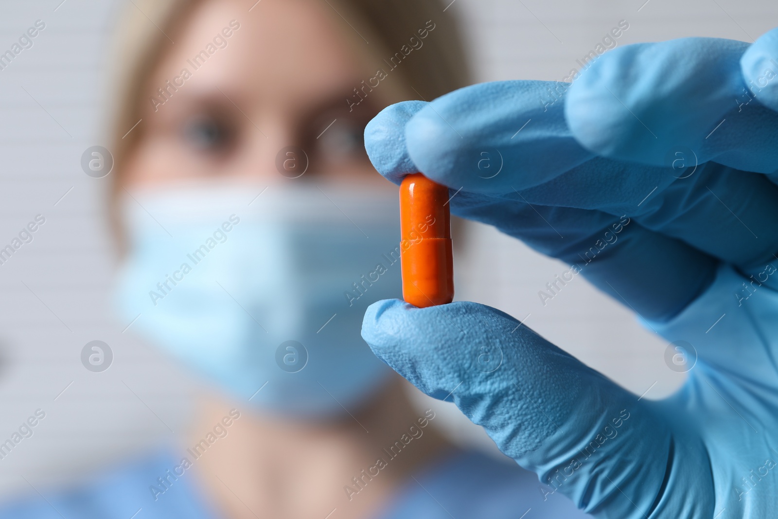 Photo of Doctor holding pill on light background, selective focus