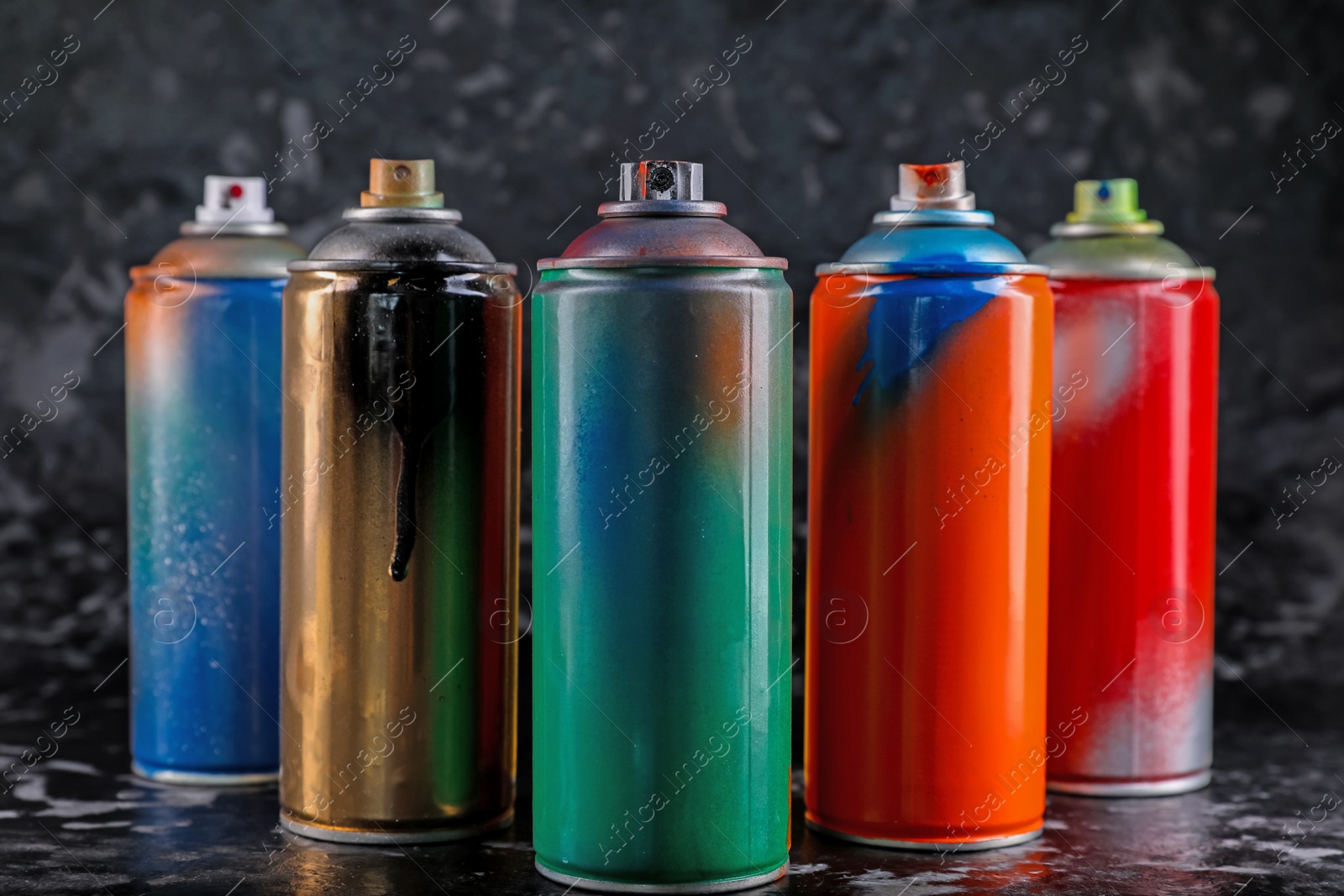 Photo of Used cans of spray paint on black marble background