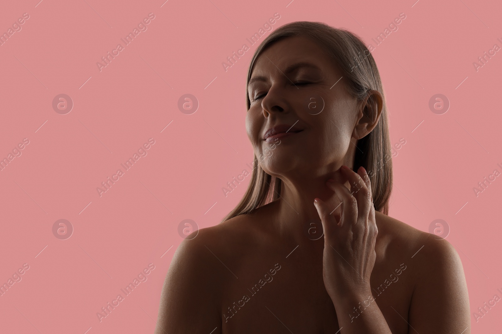 Photo of Beautiful woman touching her neck on pink background, space for text