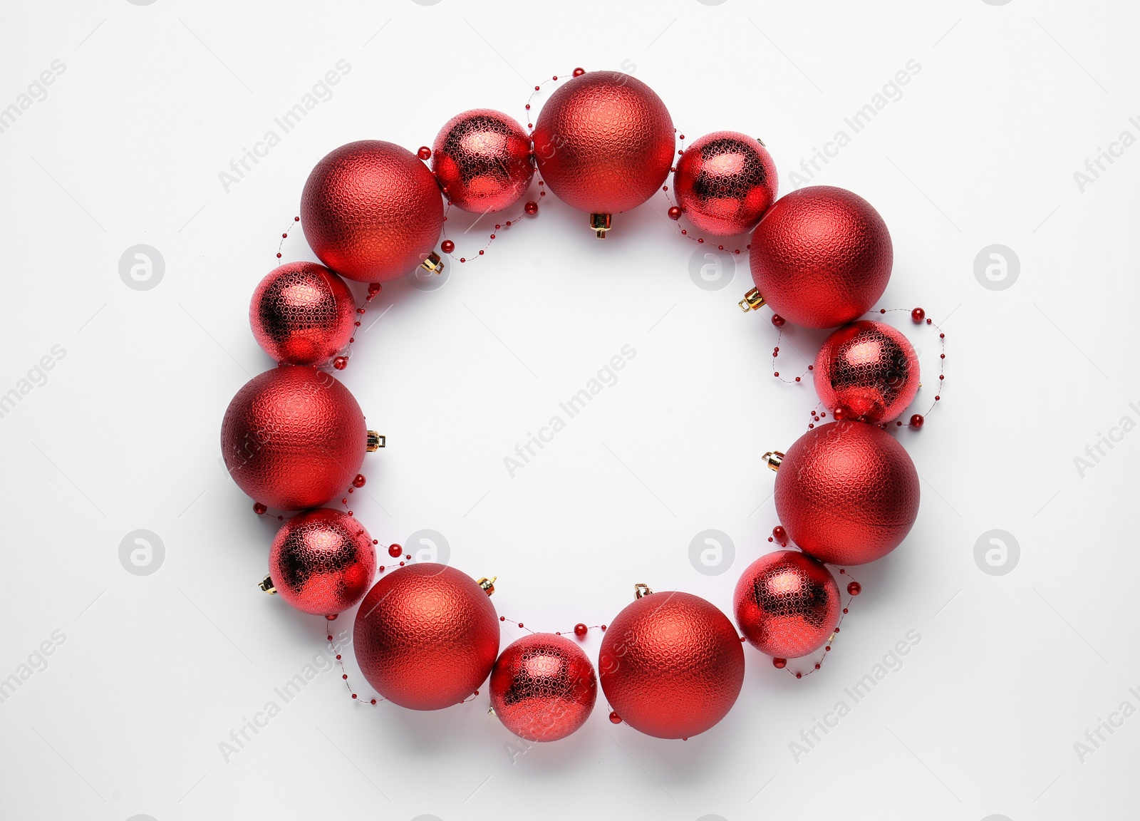 Photo of Beautiful festive wreath made of red Christmas balls on white background, top view