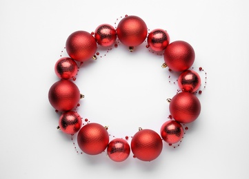 Beautiful festive wreath made of red Christmas balls on white background, top view