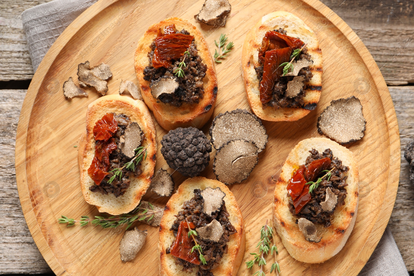 Photo of Delicious bruschettas with truffle sauce and sun dried tomatoes on wooden table, top view