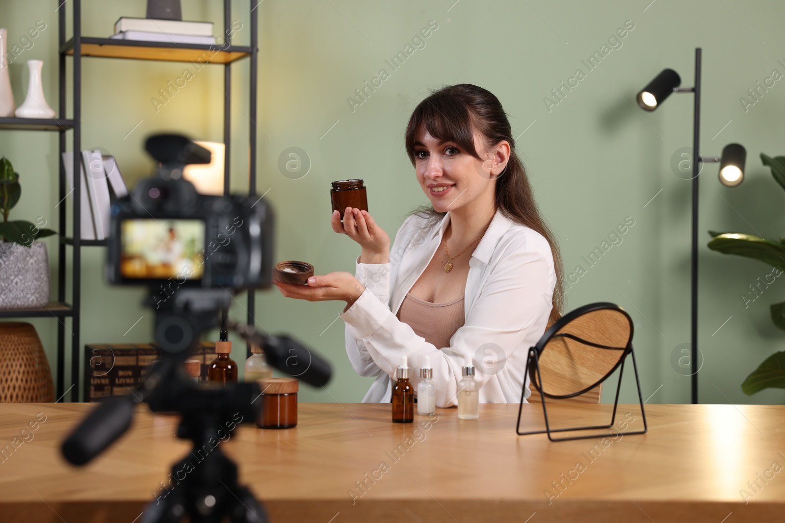 Photo of Smiling beauty blogger recording video while testing cosmetic products at home