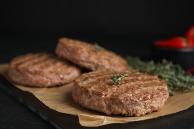 Photo of Tasty grilled hamburger patties with thyme on black table, closeup