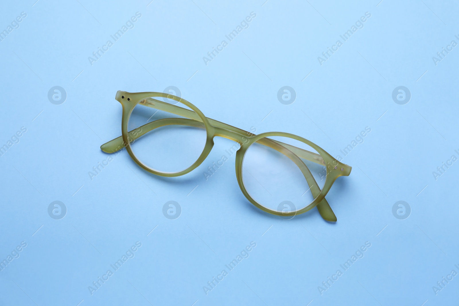 Photo of Glasses with corrective lenses on light blue background, top view