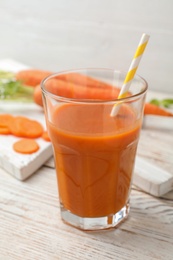 Photo of Glass of fresh carrot juice on white wooden table