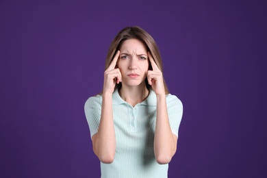 Portrait of stressed young woman on purple background