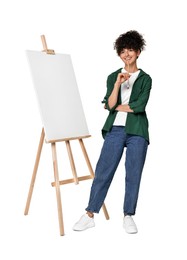 Photo of Young woman holding brush near easel with canvas against white background