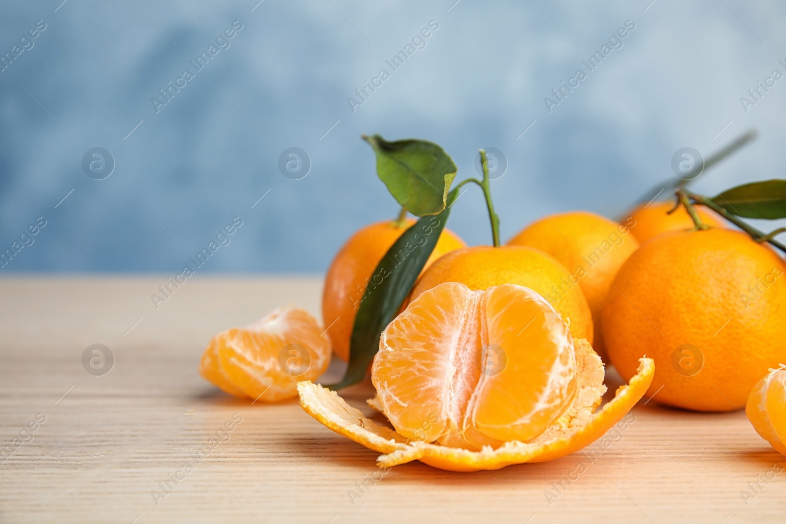 Photo of Fresh ripe tangerines with green leaves on table. Space for text