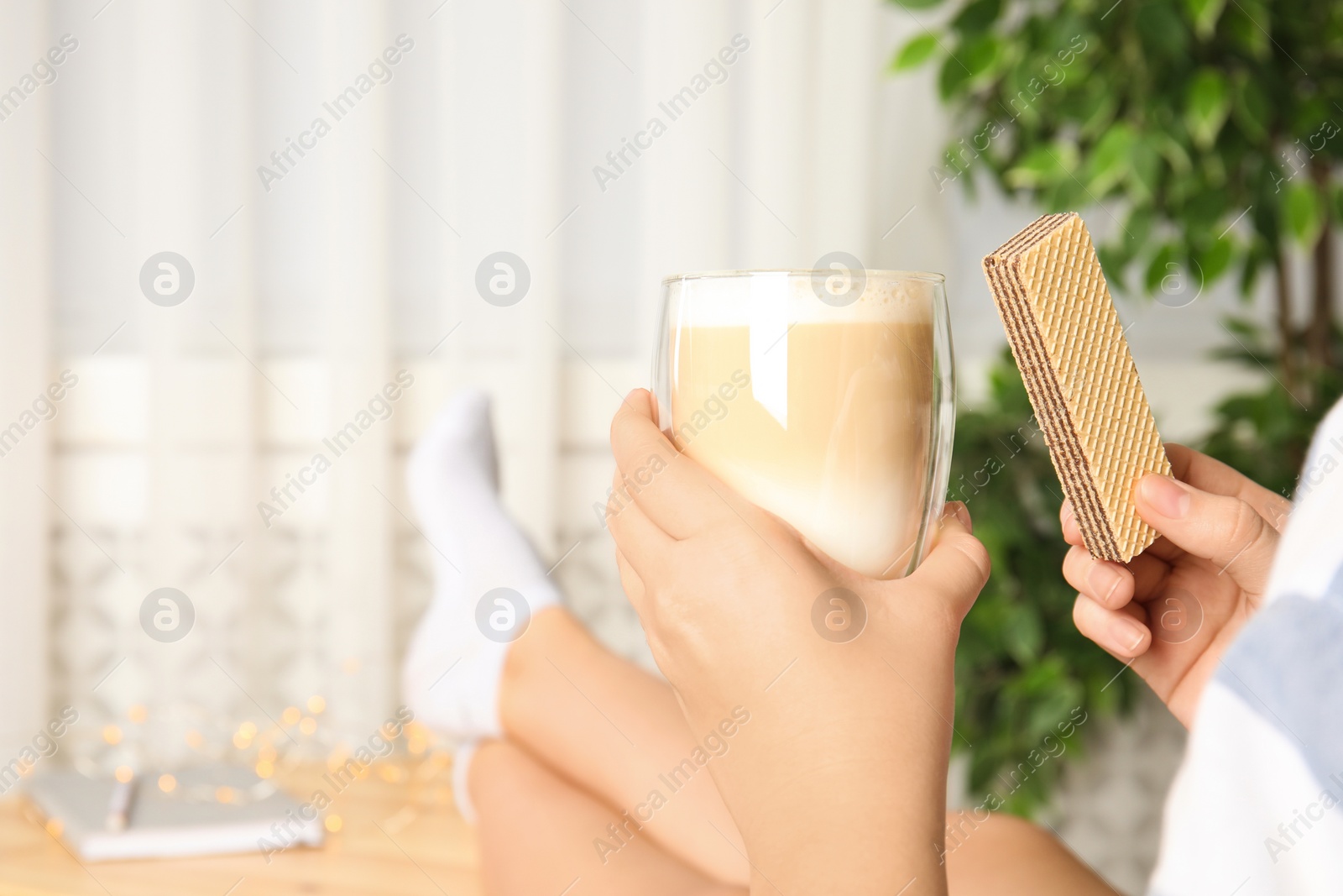 Photo of Woman having delicious wafer and coffee for breakfast indoors, closeup