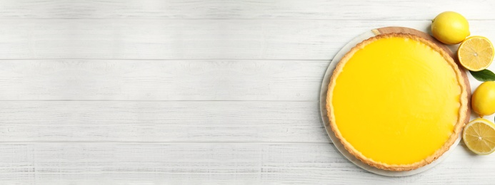 Delicious homemade lemon pie and fruits on white wooden table, flat lay. Space for text