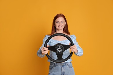 Photo of Happy young woman with steering wheel on yellow background