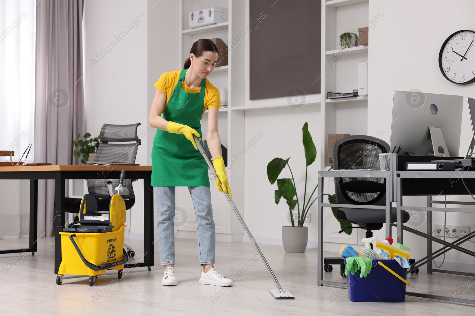 Photo of Cleaning service worker washing floor with mop. Bucket with supplies in office