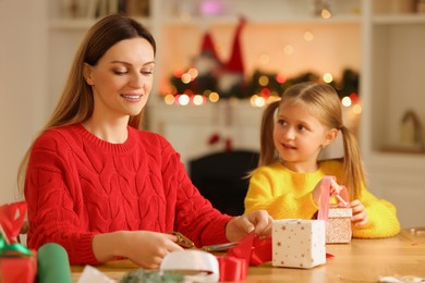 Christmas presents wrapping. Mother and her little daughter decorating gift boxes with ribbon at home, selective focus