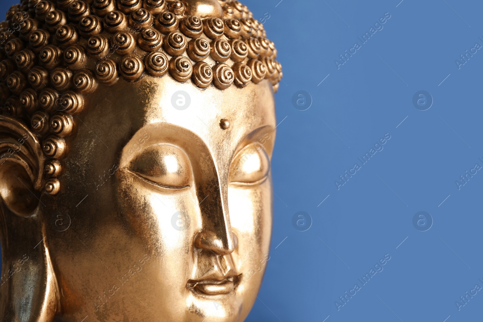 Photo of Beautiful golden Buddha sculpture on blue background, closeup. Space for text