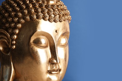 Beautiful golden Buddha sculpture on blue background, closeup. Space for text