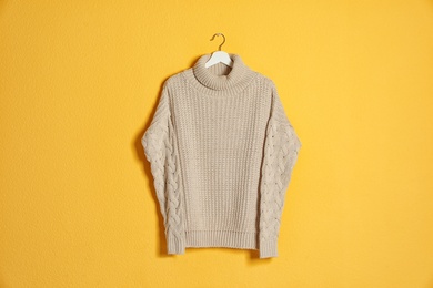 Hanger with stylish sweater on color background