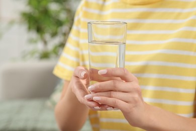 Healthy habit. Closeup of woman holding glass with fresh water indoors