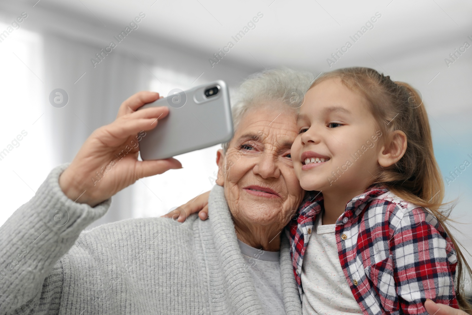 Photo of Cute girl and her grandmother taking selfie  at home