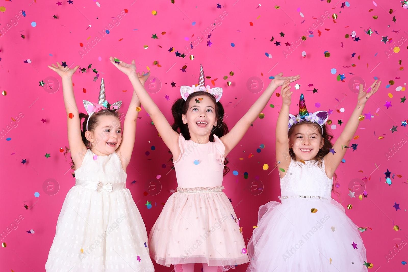 Photo of Adorable little children and falling confetti on pink background