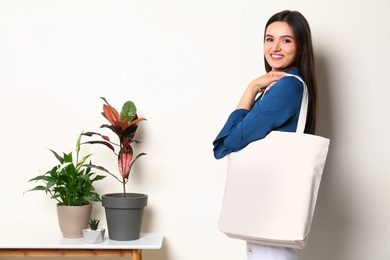 Photo of Beautiful young woman with stylish blank eco bag against color background