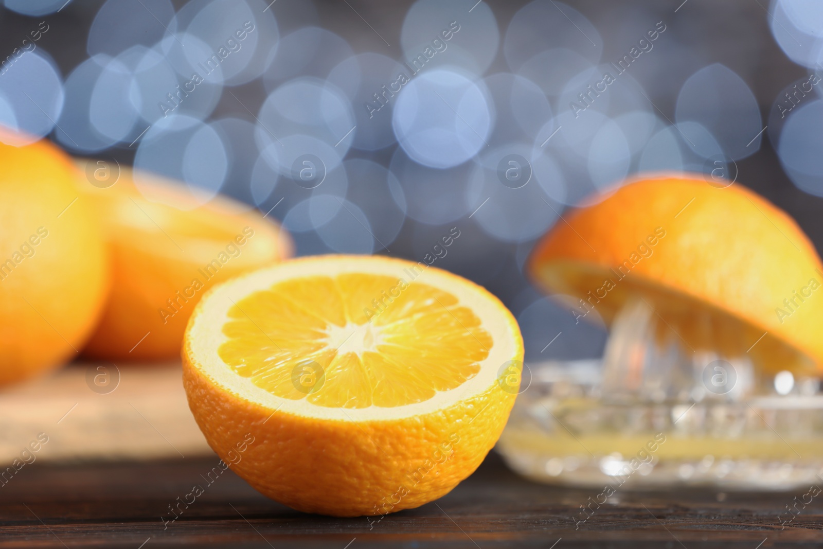 Photo of Cut fresh orange on table against blurred lights