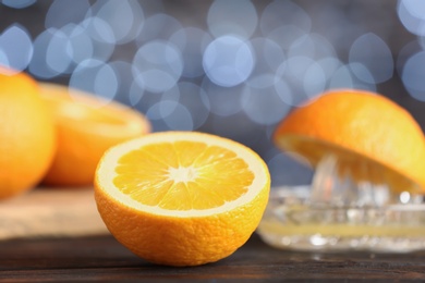 Photo of Cut fresh orange on table against blurred lights