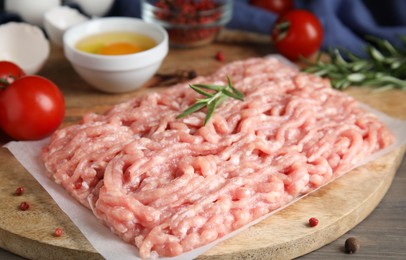Photo of Raw chicken minced meat with rosemary on grey wooden table, closeup