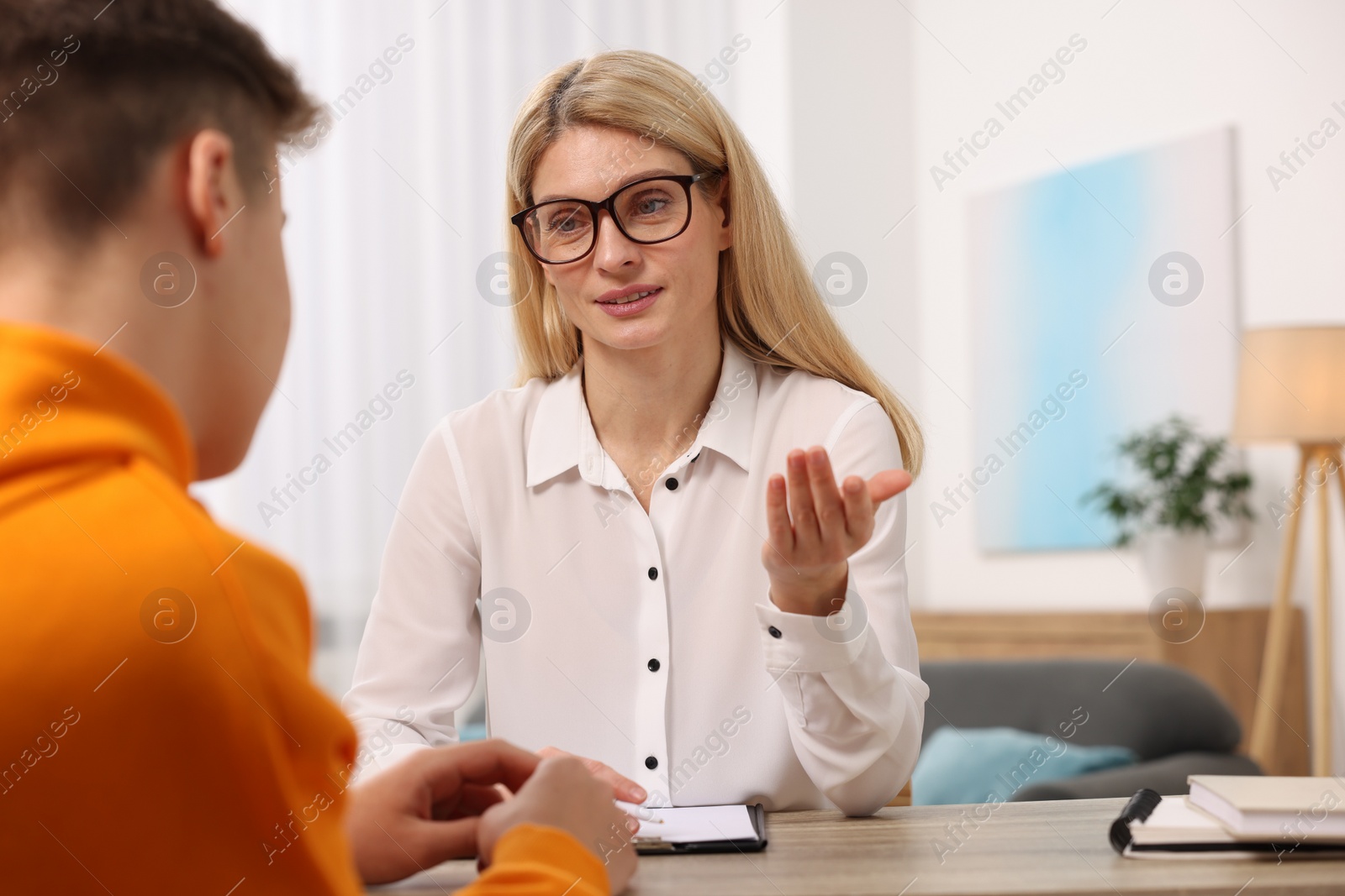 Photo of Psychologist working with teenage boy at table in office