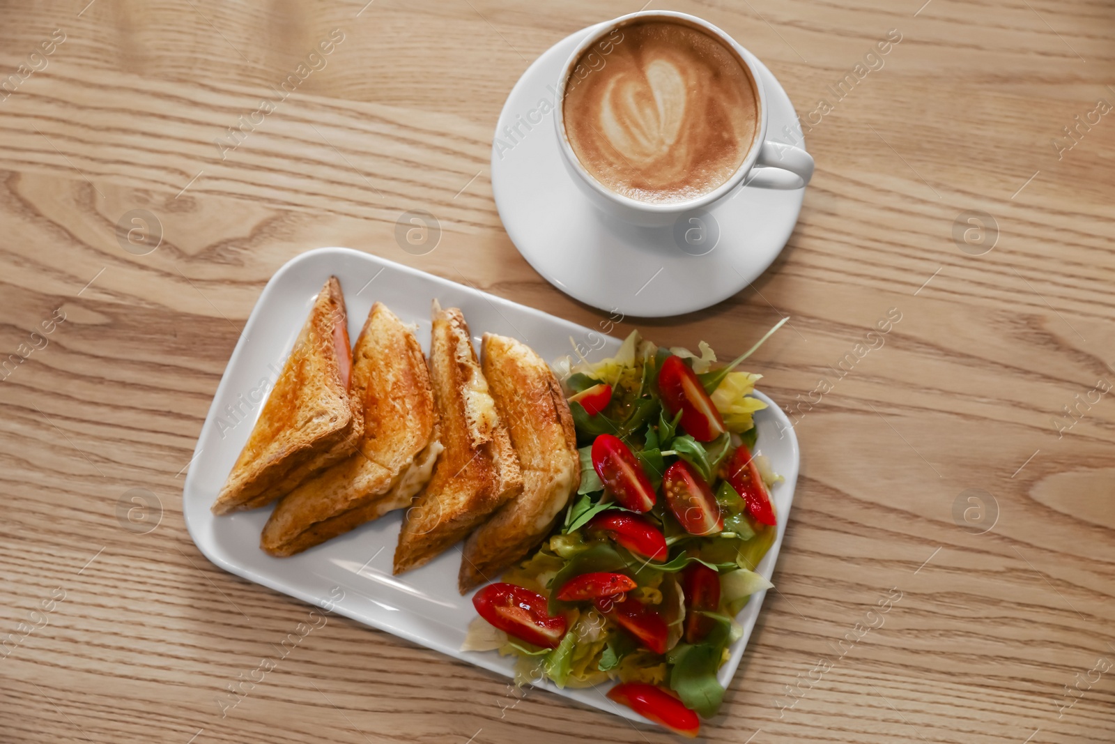 Photo of Plate of delicious toasts with salad and coffee cup on wooden table, flat lay