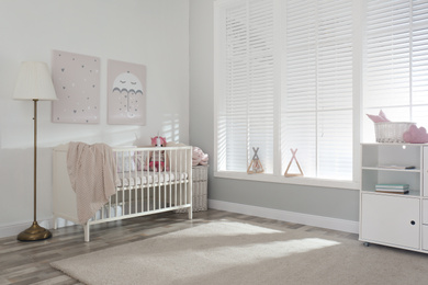 Stylish baby room interior with crib and cute pictures on wall