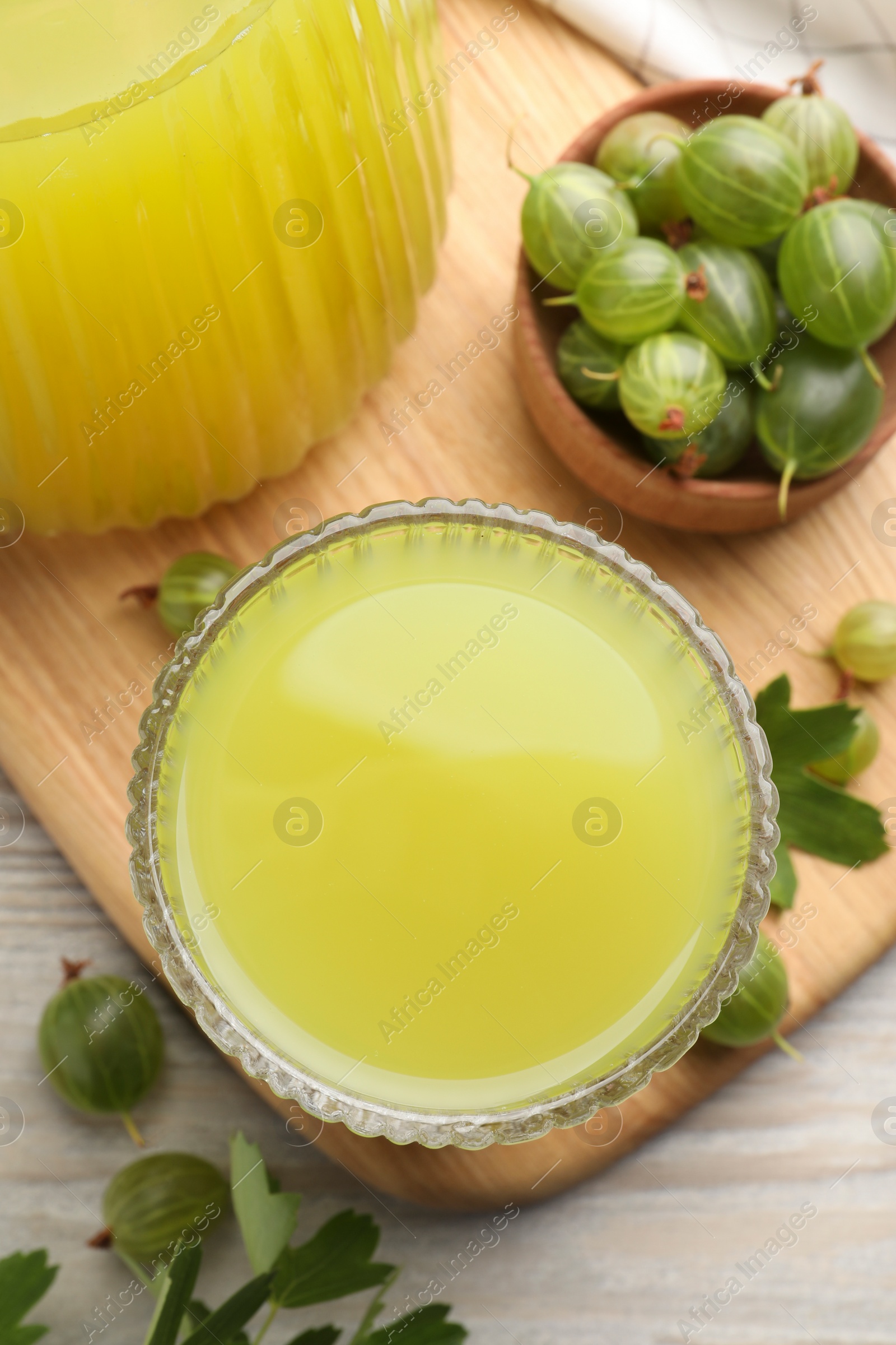 Photo of Tasty gooseberry juice and fresh berries on wooden table, closeup