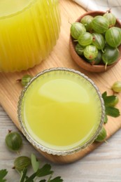 Tasty gooseberry juice and fresh berries on wooden table, closeup