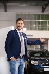 Salesman standing in modern auto dealership. Buying new car