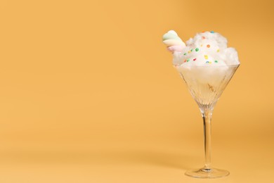 Martini glass with cotton, sprinkles and marshmallow on yellow background. Space for text