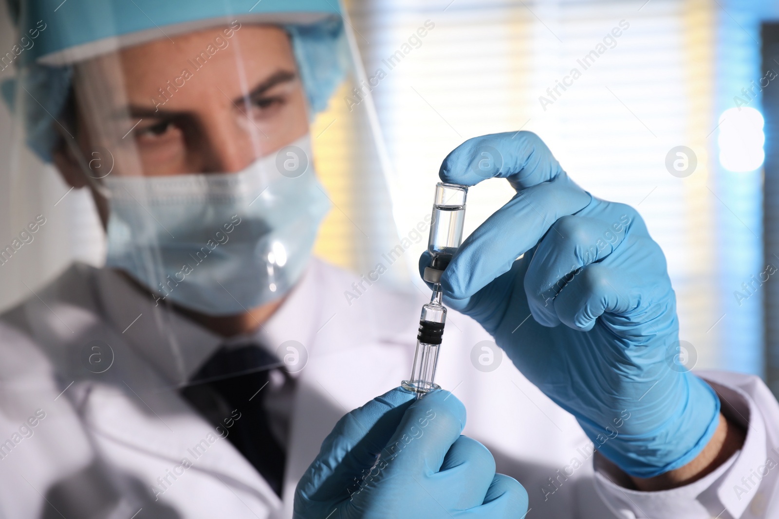 Photo of Doctor filling syringe with vaccine against Covid-19 in laboratory, focus on hands